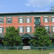 Rogues Harbor Inn Red brick building, green paneling, blue skies, two small trees in front